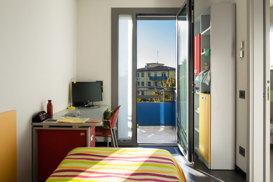 Una stanza con letto singolo, una scrivania e un balconcino della Residenza Carli