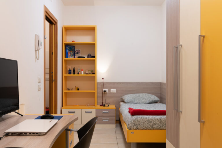 Alloggio della Residenza Colombo con un letto singolo, uno scaffale e una scrivania