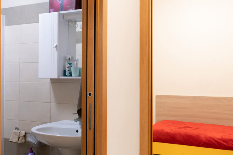 Uno scorcio di un alloggio della Residenza Colombo in cui si intravede il lavandino del bagno e il letto
